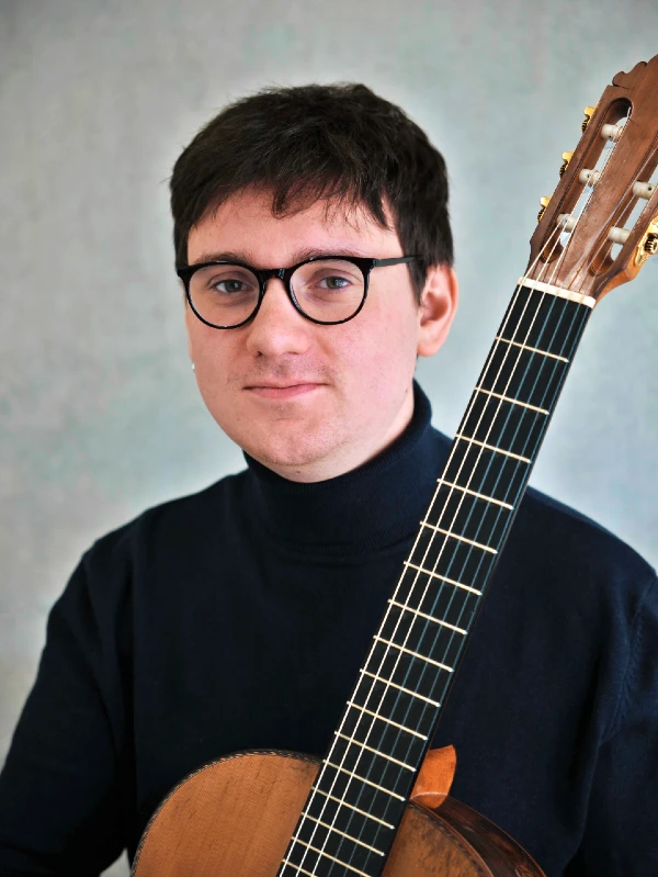 Kolja Gibbs Smith holding a classical guitar for Fogel Academy testimonial